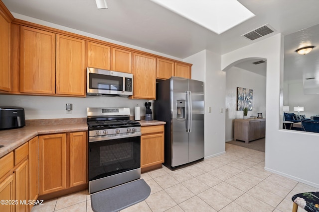 kitchen with visible vents, stainless steel appliances, arched walkways, light countertops, and light tile patterned floors