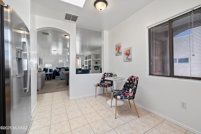 hallway with light tile patterned floors, baseboards, and visible vents