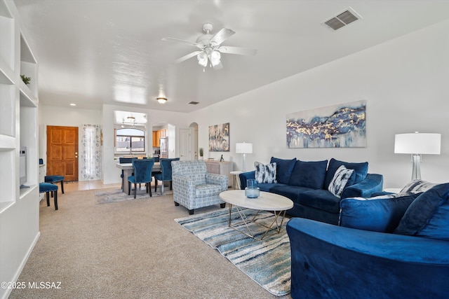 living room with light carpet, visible vents, arched walkways, and a ceiling fan