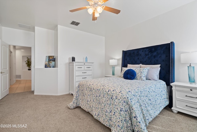 bedroom with visible vents, light colored carpet, and a ceiling fan