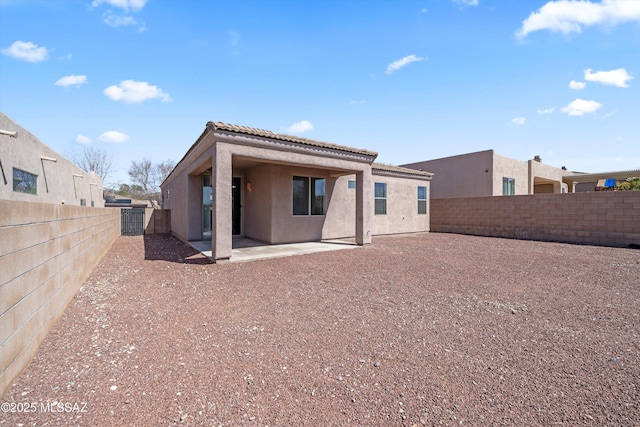 back of property featuring a tiled roof, stucco siding, a fenced backyard, and a patio area