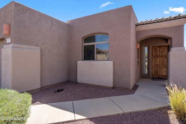 doorway to property with stucco siding and a tiled roof