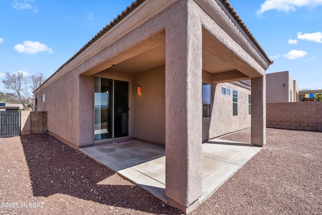 back of house featuring a tiled roof, stucco siding, a patio, and fence