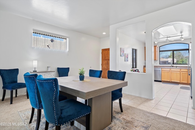 dining area featuring light tile patterned floors, light colored carpet, rail lighting, and baseboards