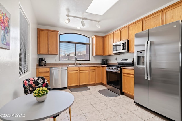 kitchen featuring a sink, a skylight, light tile patterned flooring, and stainless steel appliances