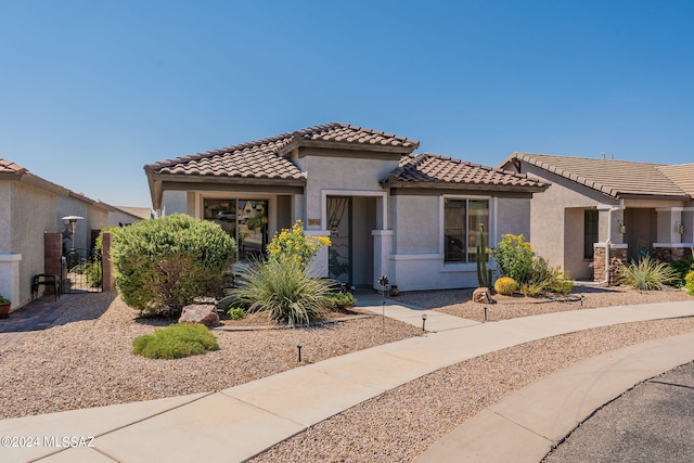 mediterranean / spanish home with a tile roof, a gate, and stucco siding