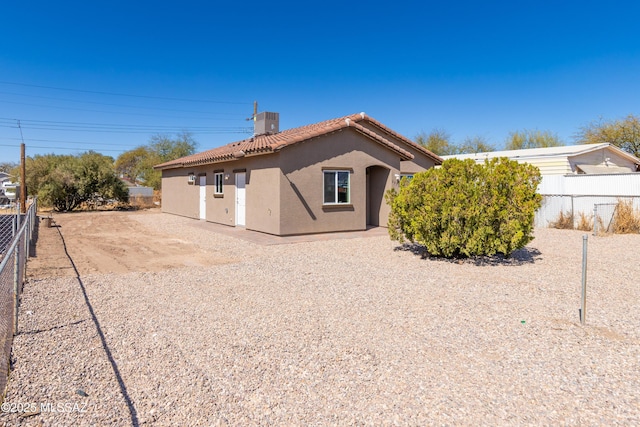 back of house with central AC unit, a tiled roof, fence, and stucco siding