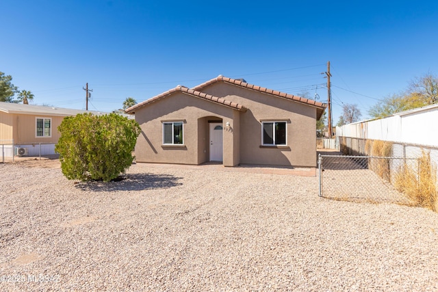 view of front of property with stucco siding, a tiled roof, and fence