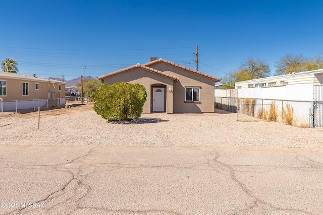 view of front of property featuring stucco siding, a tile roof, and fence