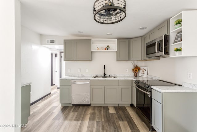 kitchen with gray cabinets, appliances with stainless steel finishes, open shelves, and a sink