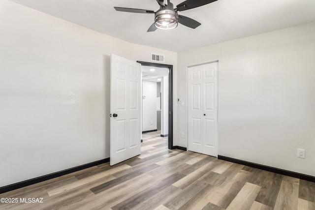 unfurnished bedroom with light wood-style flooring, visible vents, a ceiling fan, baseboards, and a closet