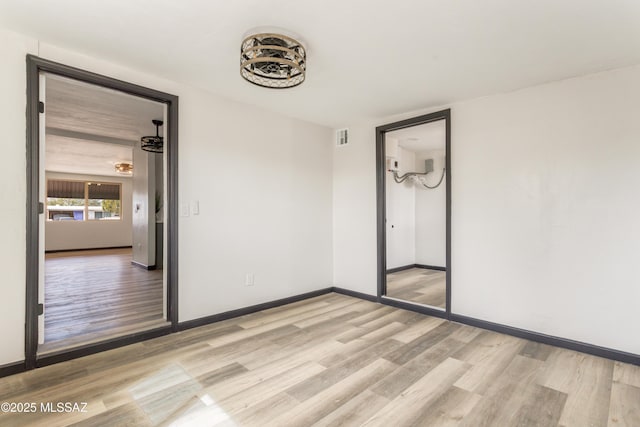 unfurnished room with visible vents, light wood-style flooring, and baseboards