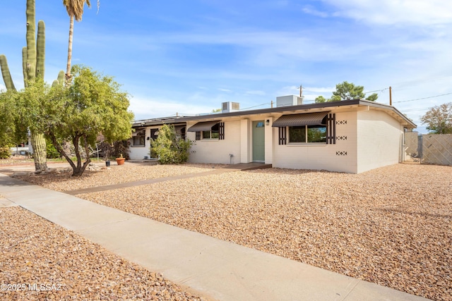 ranch-style home featuring central air condition unit, fence, and concrete block siding