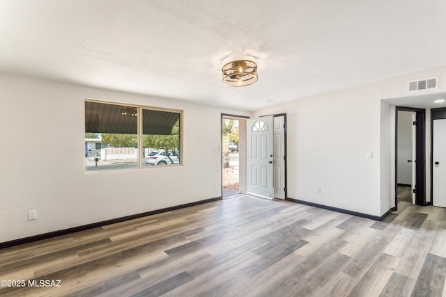 empty room with visible vents, baseboards, and wood finished floors