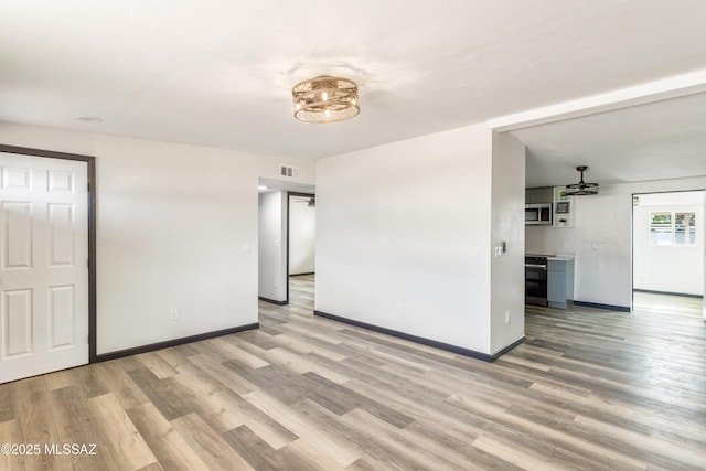 empty room with light wood-style flooring, visible vents, and baseboards