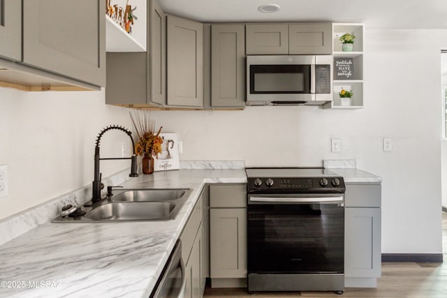 kitchen with open shelves, stainless steel appliances, light countertops, gray cabinetry, and a sink