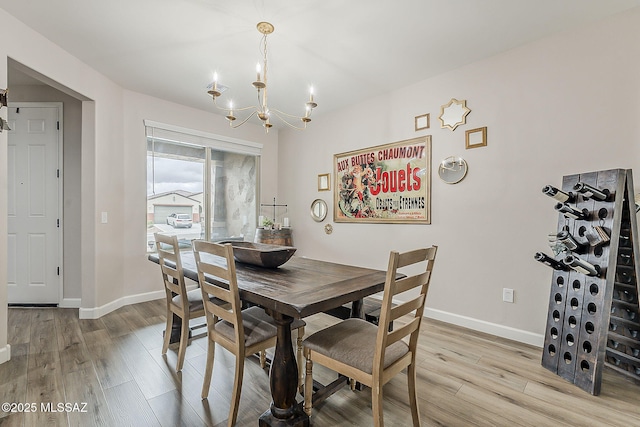 dining space with an inviting chandelier, light wood-style flooring, and baseboards