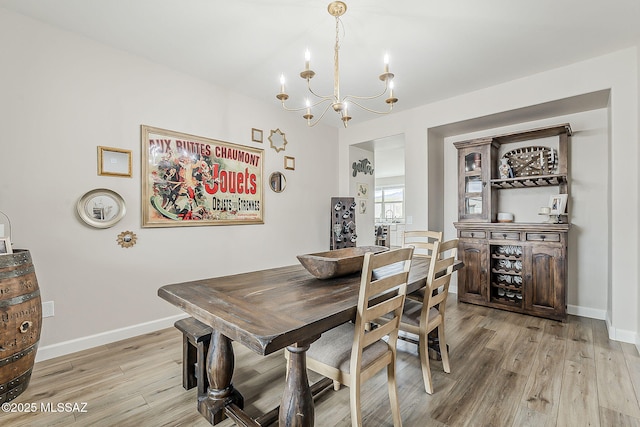 dining room featuring a chandelier, light wood-type flooring, and baseboards