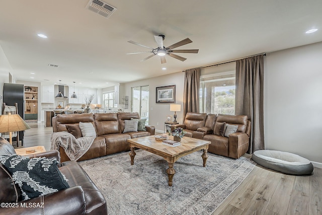 living area featuring a ceiling fan, recessed lighting, visible vents, and light wood finished floors