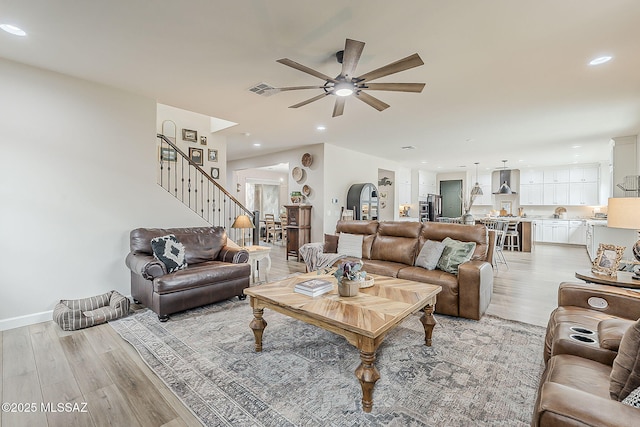 living area with light wood-style floors, recessed lighting, visible vents, and stairway