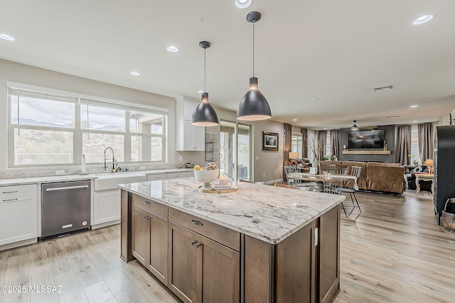 kitchen with light wood-style floors, open floor plan, white cabinetry, a sink, and a kitchen island