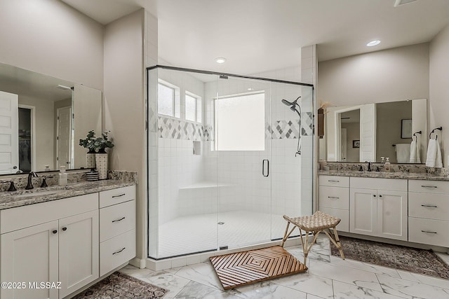 bathroom featuring marble finish floor, a stall shower, two vanities, and a sink