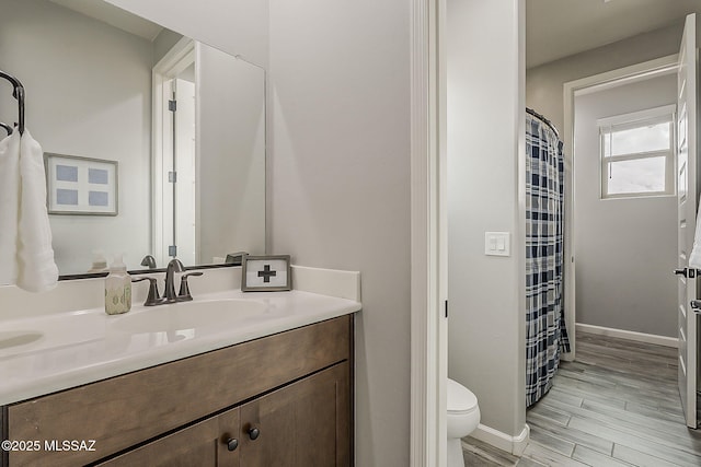 full bathroom featuring baseboards, a shower with shower curtain, toilet, wood finished floors, and vanity