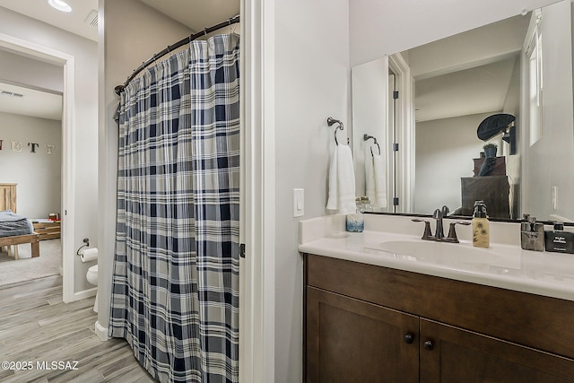 full bath featuring baseboards, a shower with shower curtain, toilet, wood finished floors, and vanity