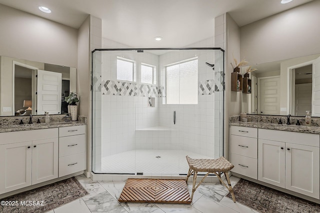 bathroom featuring marble finish floor, a sink, and a shower stall