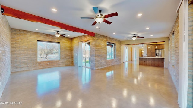 unfurnished living room featuring brick wall, concrete floors, beam ceiling, and recessed lighting