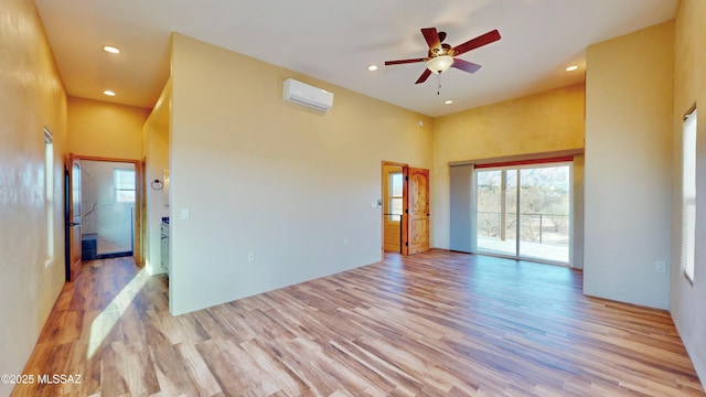 unfurnished room featuring recessed lighting, a high ceiling, wood finished floors, and a wall mounted air conditioner