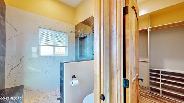 bathroom featuring toilet and a marble finish shower