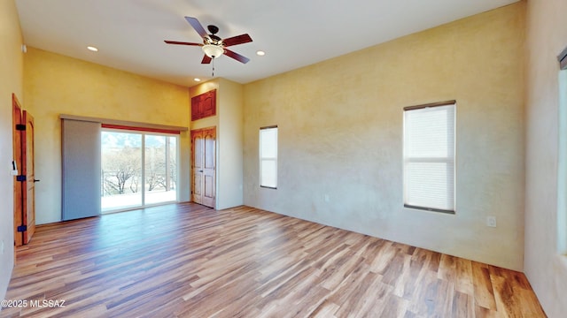 unfurnished bedroom with recessed lighting, light wood-type flooring, a high ceiling, and access to exterior