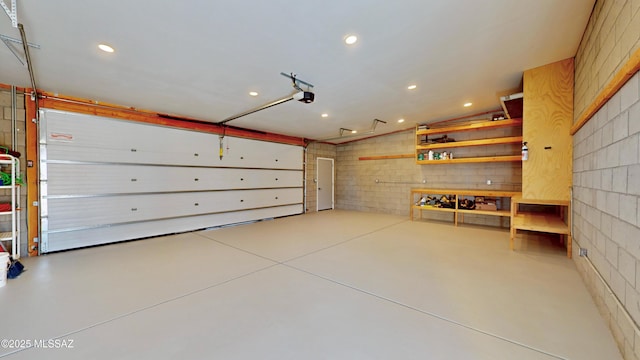 garage featuring a garage door opener, recessed lighting, and concrete block wall