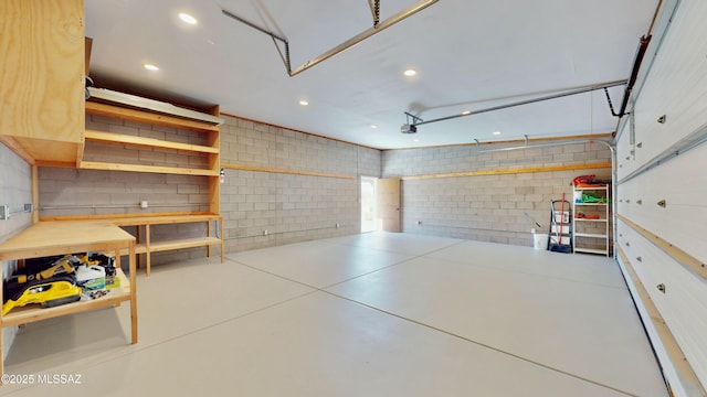 garage with a garage door opener, recessed lighting, and concrete block wall