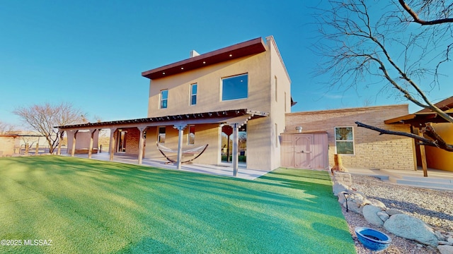 back of house featuring stucco siding, an outdoor structure, a storage unit, and a patio