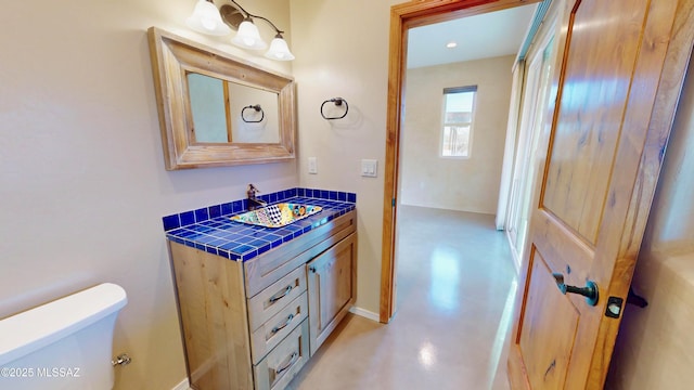 half bathroom featuring concrete flooring, vanity, and toilet