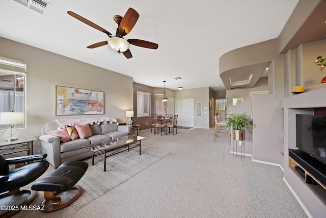 living room featuring baseboards, ceiling fan, visible vents, and light colored carpet