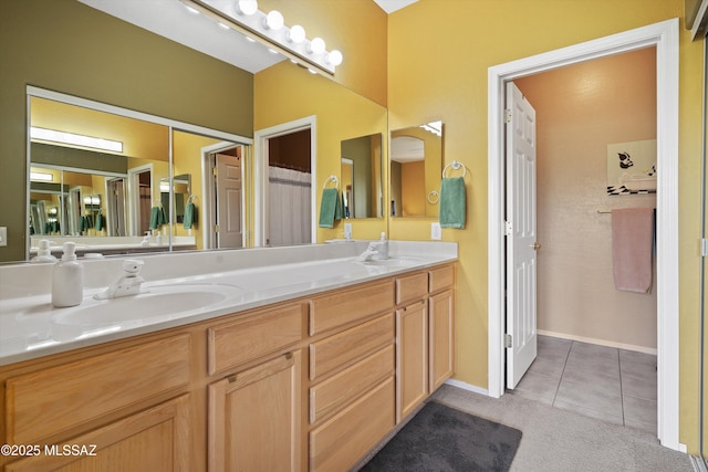 bathroom with tile patterned flooring, a sink, baseboards, and double vanity