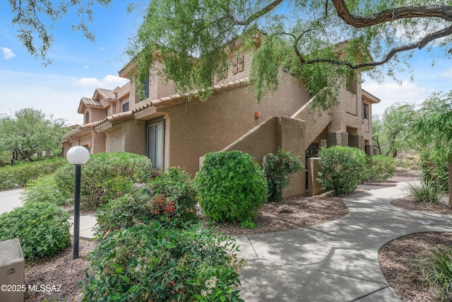 view of property exterior with a tile roof and stucco siding