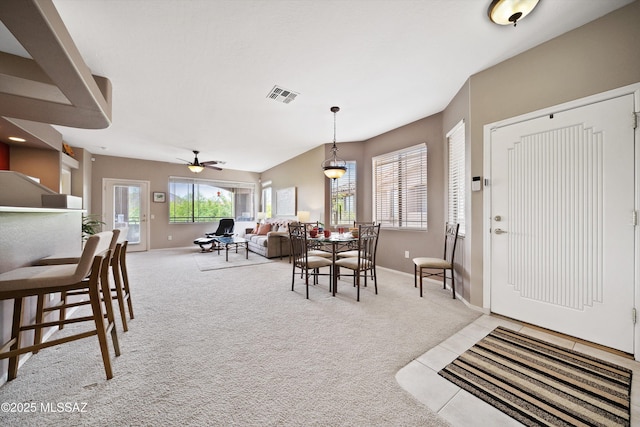 dining area featuring baseboards, visible vents, and light colored carpet