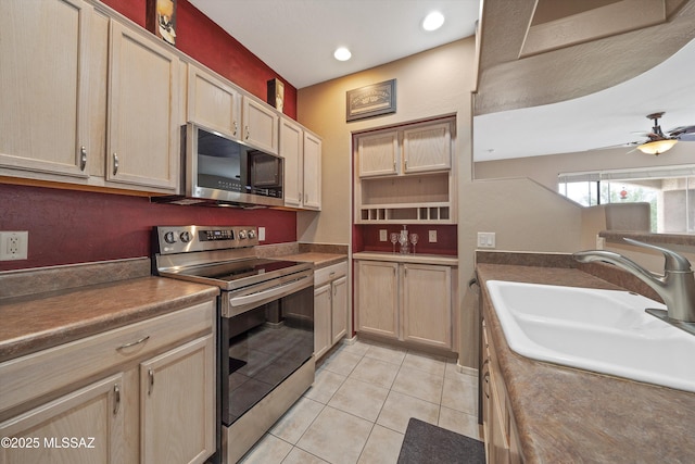 kitchen with light tile patterned floors, ceiling fan, a sink, appliances with stainless steel finishes, and dark countertops