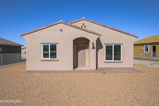 mediterranean / spanish house with a patio area, a tile roof, fence, and stucco siding