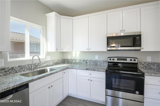 kitchen featuring stainless steel appliances, white cabinets, a sink, and light stone counters