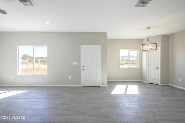 spare room featuring baseboards, dark wood-style floors, visible vents, and an inviting chandelier