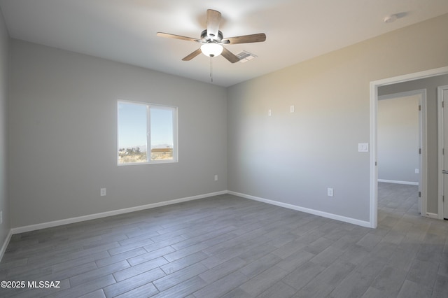 unfurnished room with a ceiling fan, visible vents, baseboards, and wood finished floors