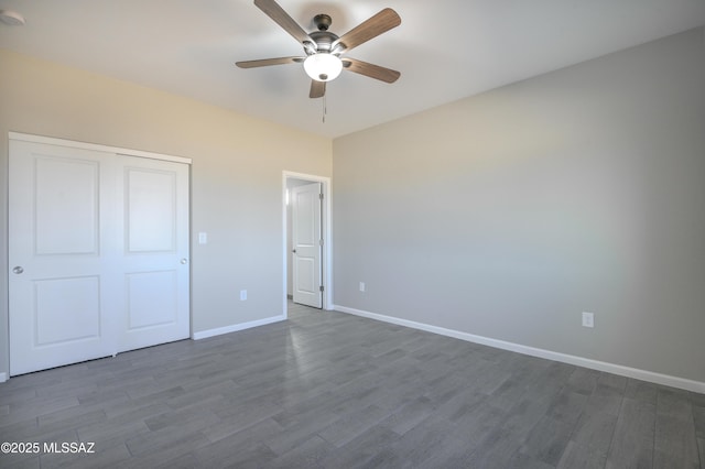 unfurnished bedroom featuring ceiling fan, dark wood-type flooring, a closet, and baseboards