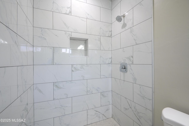 bathroom featuring tiled shower and toilet