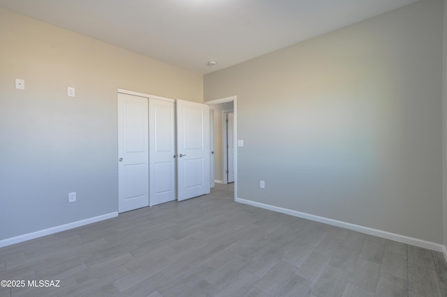 unfurnished bedroom featuring a closet, baseboards, and wood finished floors