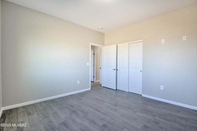 unfurnished bedroom with a closet, wood finished floors, and baseboards